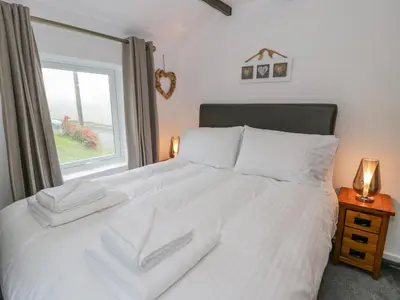 a bedroom with a white bed with a window at Cae Lleci in Dolgellau