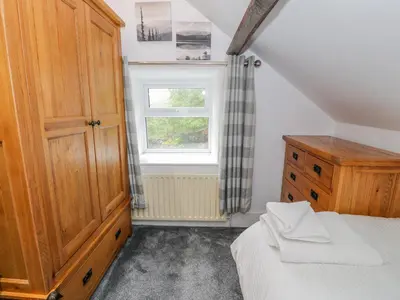 a bedroom with a bed and a dresser and a window at Cae Lleci in Dolgellau