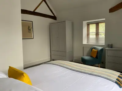 a bedroom with a bed and a blue chair at The Retreat in Bredwardine
