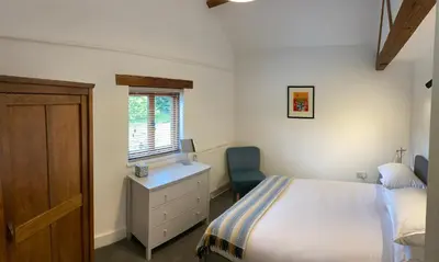 a bedroom with a bed and a desk and a window at The Retreat in Bredwardine