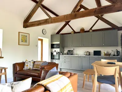 a living room with couches and a table and a kitchen at The Retreat in Bredwardine