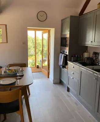 a kitchen with a table and a clock on the wall at The Retreat in Bredwardine