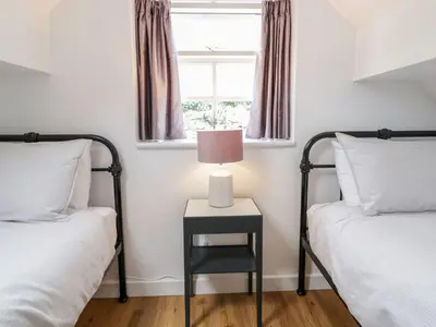 a bedroom with two beds and a table with a lamp at The Toll House in Dolgellau