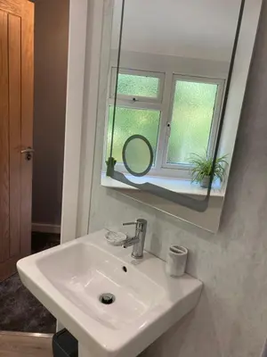 a bathroom with a white sink and a mirror at Ty Gles in Derwenlas