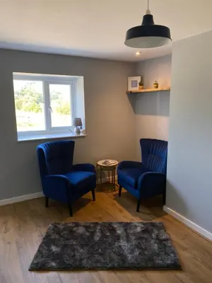 a waiting room with two blue chairs and a table at Ty Gles in Derwenlas