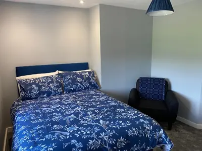 a bedroom with a blue bed and a chair at Ty Gles in Derwenlas