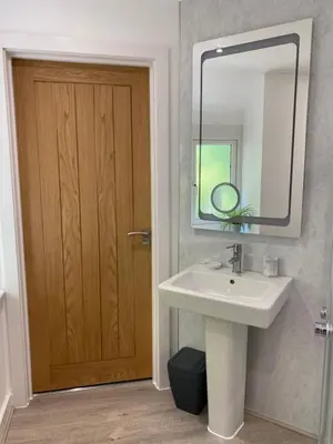 a bathroom with a sink and a wooden door at Ty Gles in Derwenlas