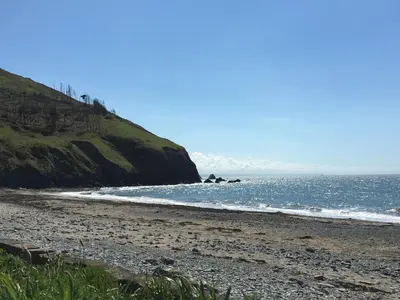 a beach with a rocky shore and the ocean at Ty Gles in Derwenlas
