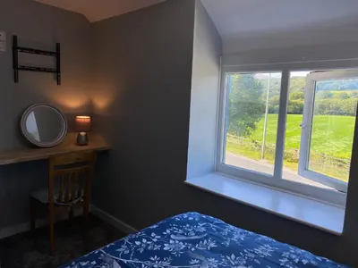 a bedroom with a bed and a mirror and a window at Ty Gles in Derwenlas