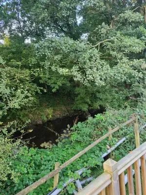 a wooden fence in front of a river with trees at Glamping Hut - Sleeps 2 hot tub & parking in Welshpool