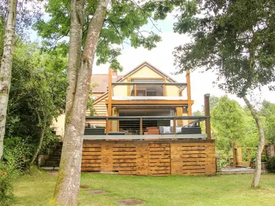 a house with a wrap around deck with trees at Sunnyside in Leominster