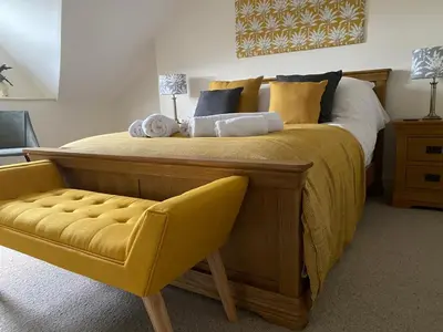 a bedroom with a large bed with a yellow chair at No6 in Barmouth