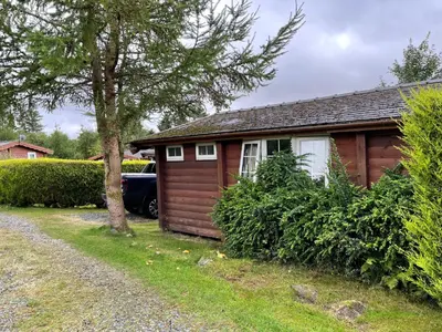 a small house with a car parked in front of it at Cosy 2 bedroom Log Cabin in Snowdonia Cabin151 in Trawsfynydd