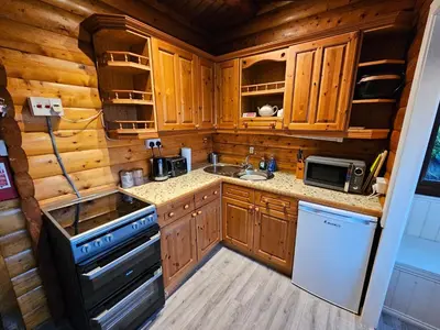 a kitchen with wooden cabinets and a stove and a sink at Cosy 2 bedroom Log Cabin in Snowdonia Cabin151 in Trawsfynydd