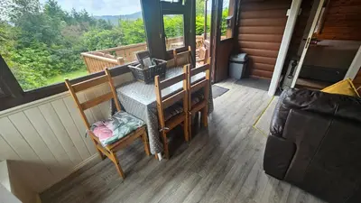 a porch with a table and chairs and a window at Cosy 2 bedroom Log Cabin in Snowdonia Cabin151 in Trawsfynydd