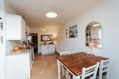 a kitchen and dining room with a wooden table and chairs at 13 Tabernacle Street - Aberaeron in Aberaeron