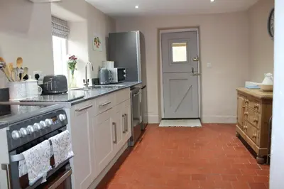 a kitchen with white cabinets and a red tile floor at Avondale in Llangollen