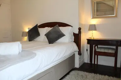 a bedroom with a bed with white sheets and pillows at Avondale in Llangollen