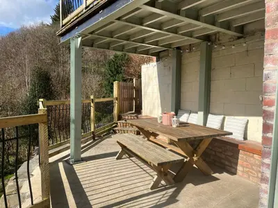 a wooden deck with a picnic table on a porch at Avondale in Llangollen