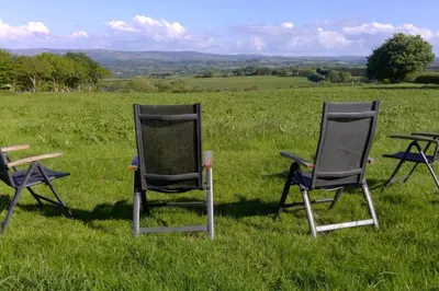 three chairs sitting in the grass in a field at 2 Bed Rural cottage between the mountains and Sea in West Wales in Lampeter