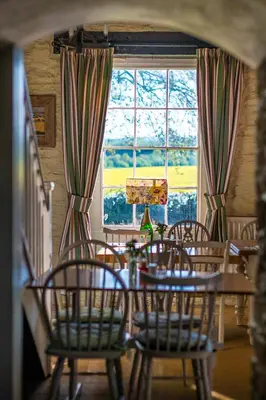 a dining room with a table and chairs and a window at The Powis Arms in North Lydbury
