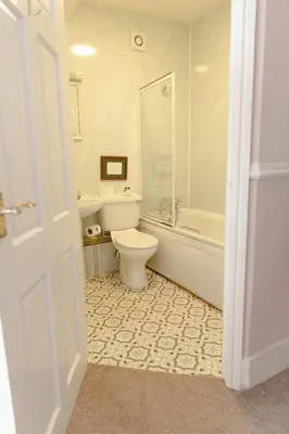 a white bathroom with a toilet and a bath tub at The Powis Arms in North Lydbury