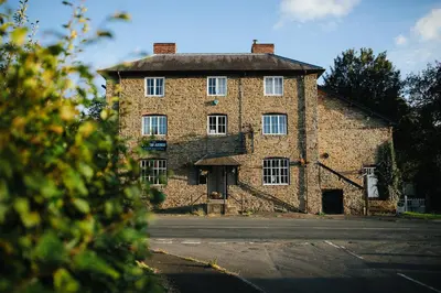 a large brick building with white windows on a street at The Powis Arms in North Lydbury