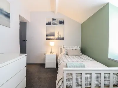 a bedroom with a bed with a white crib at Arthurs Cottage in Tywyn