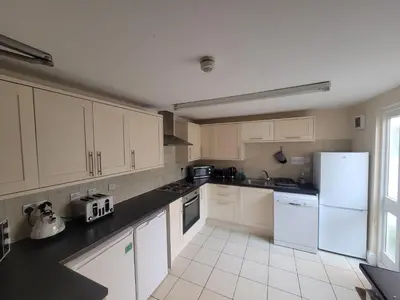a kitchen with white cabinets and a white refrigerator at Large 5 bed town-centre home close to the beach, sleeps 9 in Aberystwyth