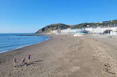 a group of people on a beach near the ocean at Large 5 bed town-centre home close to the beach, sleeps 9 in Aberystwyth