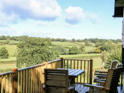 a wooden deck with chairs and a table on it at Callow Fold in Craven Arms