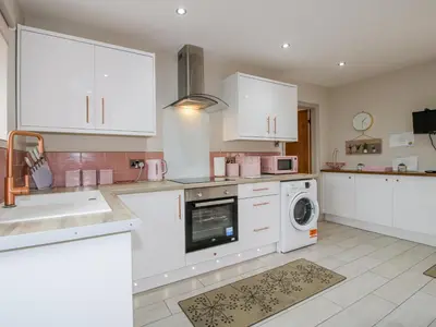 a kitchen with white cabinets and a washer and dryer at Meadow Barn in Craven Arms