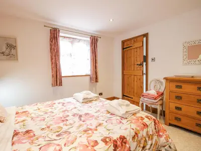 a bedroom with a bed and a dresser and a window at Meadow Barn in Craven Arms