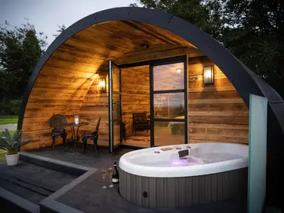 a large tub sitting in front of a wooden house at The Piglet Pod in Llanarth