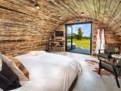 a bedroom with a large bed in a wooden wall at The Piglet Pod in Llanarth