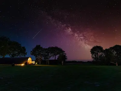 a barn in a field at night with the milky way at The Piglet Pod in Llanarth