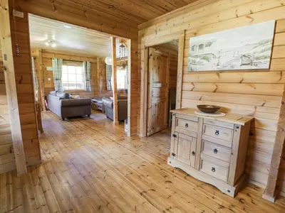 a living room with wooden walls and a wooden floor at Sun View Lodge in Llanbedr