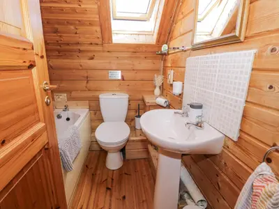 a wooden bathroom with a toilet and a sink at Sun View Lodge in Llanbedr