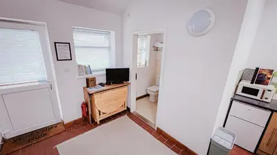 a room with a desk with a computer and a microwave at Wild Valley Bunkhouse in Llanrhaeadr-ym-Mochnant
