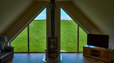 a living room with a fireplace and a large window at Holly Lodge in Welshpool
