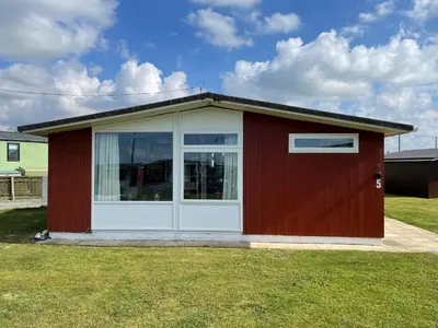 a red and white shed with a white door at Modern Funky Private Chalet at the Beach in Tywyn