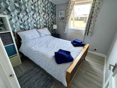 a bedroom with a bed with two blue pillows on it at Modern Funky Private Chalet at the Beach in Tywyn