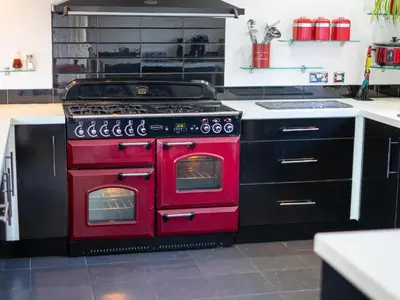 a red oven in a kitchen with black cabinets at The Old Post Office in Llandrindod Wells