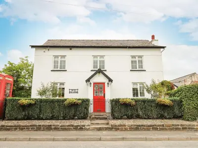 a white house with a red door and two red phones at The Old Post Office in Llandrindod Wells