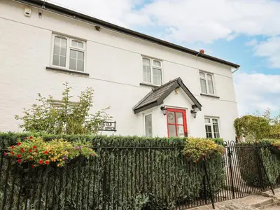 a white house with a red door and a fence at The Old Post Office in Llandrindod Wells