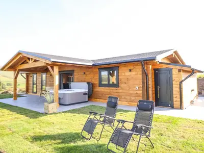 a small cabin with four chairs in the grass at Bacheiddon Log Cabin in Machynlleth