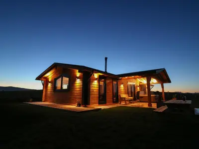 a log cabin with a porch at night at Bacheiddon Log Cabin in Machynlleth