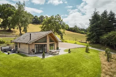 a small log cabin with a picnic table in the grass at Lower Tumble Cottage in Llandyssil