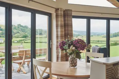 a dining room with a table with flowers on it at Lower Tumble Cottage in Llandyssil