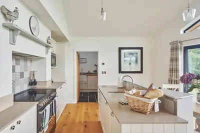a kitchen with a sink and a counter with a basket at Lower Tumble Cottage in Llandyssil